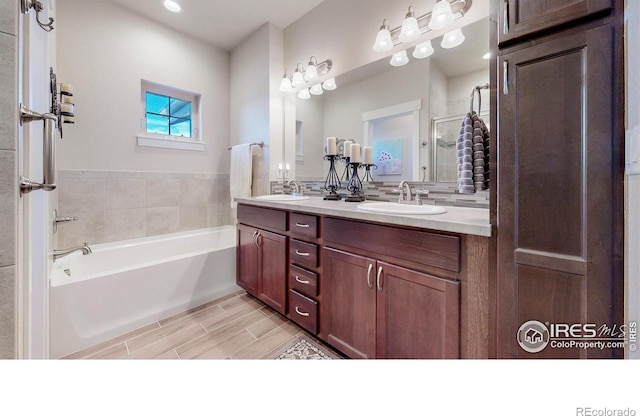 full bath with wood tiled floor, double vanity, a sink, and a bath