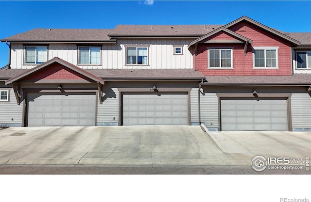 townhome / multi-family property with a garage, roof with shingles, and board and batten siding