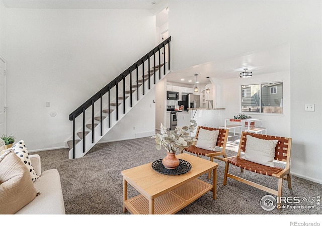 living room with baseboards, carpet flooring, stairway, and a high ceiling