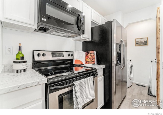 kitchen featuring light stone counters, stainless steel appliances, visible vents, light wood-style flooring, and white cabinets