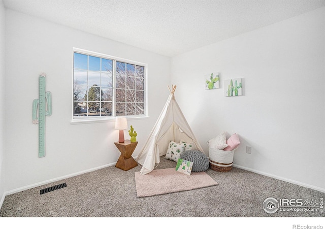 rec room featuring a textured ceiling, carpet floors, visible vents, and baseboards