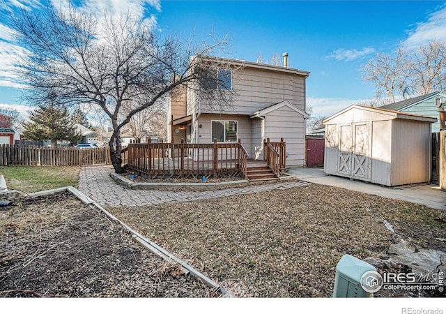 rear view of house featuring a storage shed, a deck, an outdoor structure, and a fenced backyard