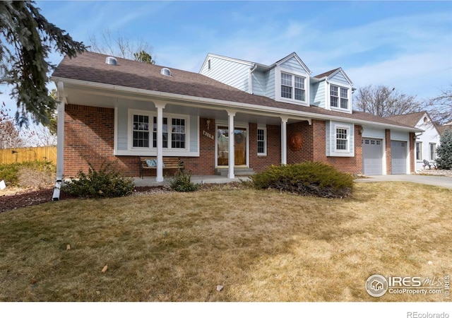 view of front facade with a porch, brick siding, fence, concrete driveway, and a front yard