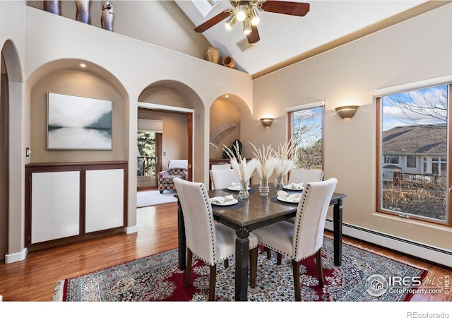 dining space with ceiling fan, high vaulted ceiling, wood finished floors, visible vents, and baseboard heating