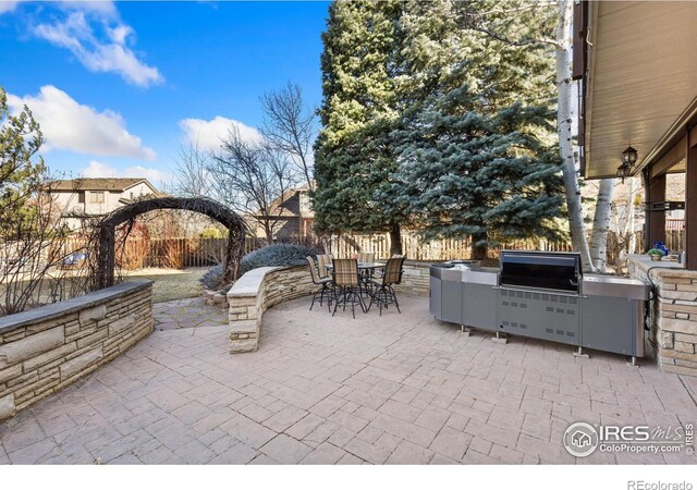 view of patio / terrace featuring exterior kitchen, outdoor dining area, and fence