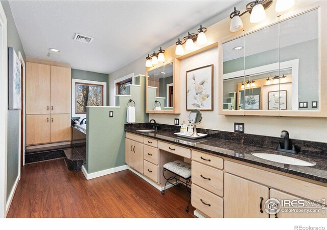 bathroom with double vanity, visible vents, a sink, and wood finished floors