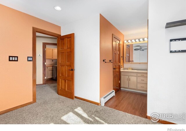 interior space with baseboards, a baseboard radiator, carpet floors, a sink, and recessed lighting