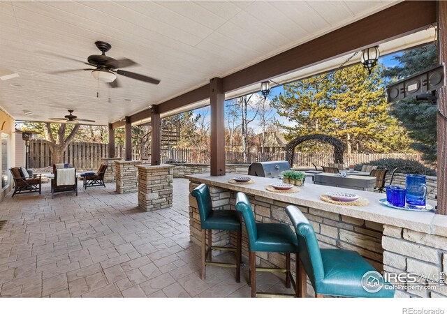 view of patio / terrace with outdoor dry bar, grilling area, area for grilling, a fenced backyard, and an outdoor living space