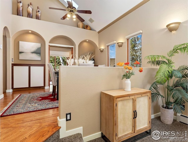 foyer entrance featuring lofted ceiling, ceiling fan, a baseboard radiator, and visible vents