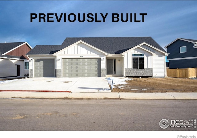 view of front facade featuring brick siding, board and batten siding, fence, a garage, and driveway