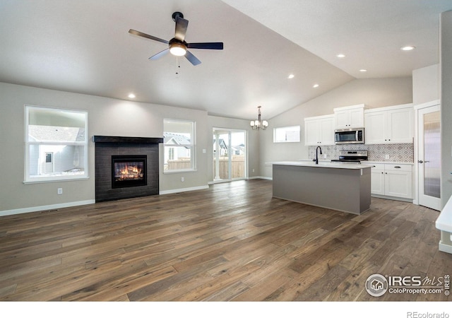 kitchen with dark wood-style floors, appliances with stainless steel finishes, open floor plan, white cabinets, and a sink