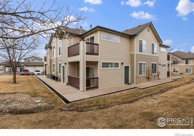 rear view of property with cooling unit, a patio, and a balcony