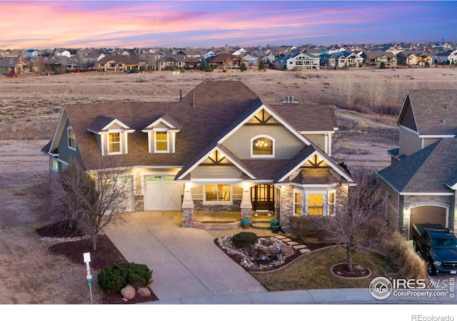 view of front of house featuring a residential view, stone siding, an attached garage, and concrete driveway