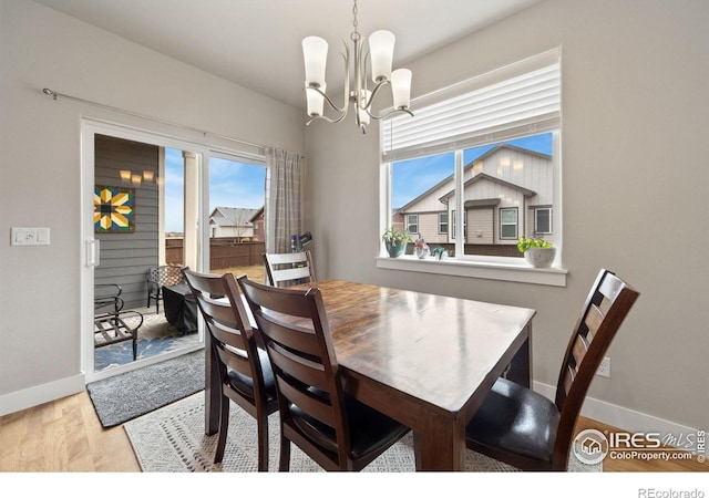 dining area with baseboards, wood finished floors, and an inviting chandelier