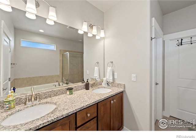 full bath featuring double vanity, a stall shower, visible vents, and a sink