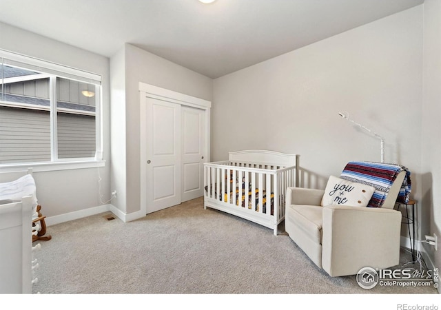 bedroom with a crib, a closet, carpet flooring, and baseboards