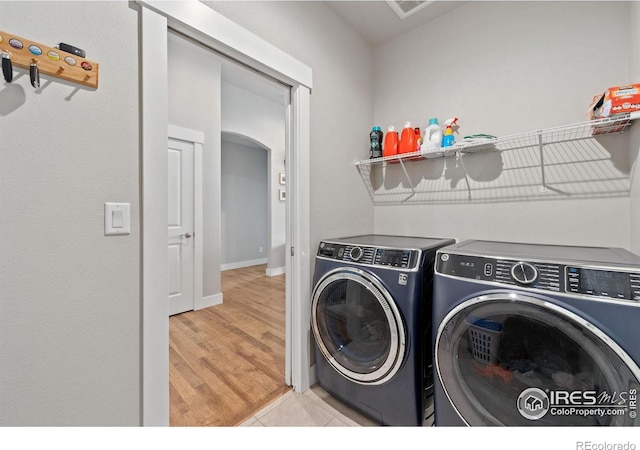 clothes washing area featuring laundry area, separate washer and dryer, and light wood-style floors