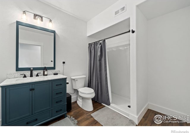 full bathroom featuring baseboards, toilet, a shower with curtain, wood finished floors, and vanity