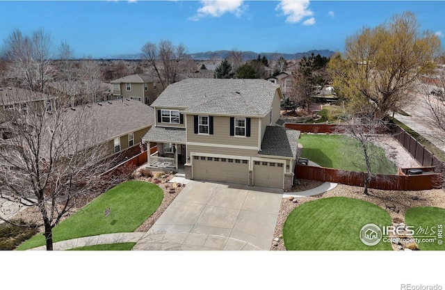 view of front facade with a shingled roof, concrete driveway, fence, a garage, and a front lawn