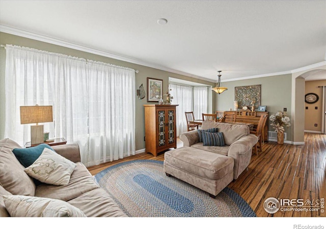 living room with arched walkways, crown molding, baseboards, and wood finished floors