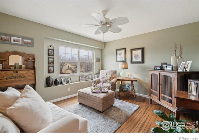 living room with wood finished floors, a ceiling fan, and baseboards