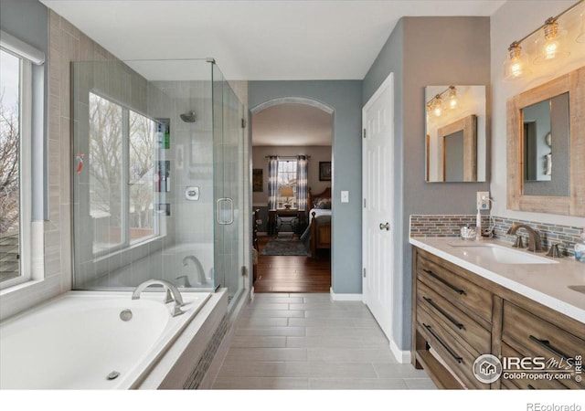 ensuite bathroom with ensuite bathroom, vanity, backsplash, a shower stall, and a bath