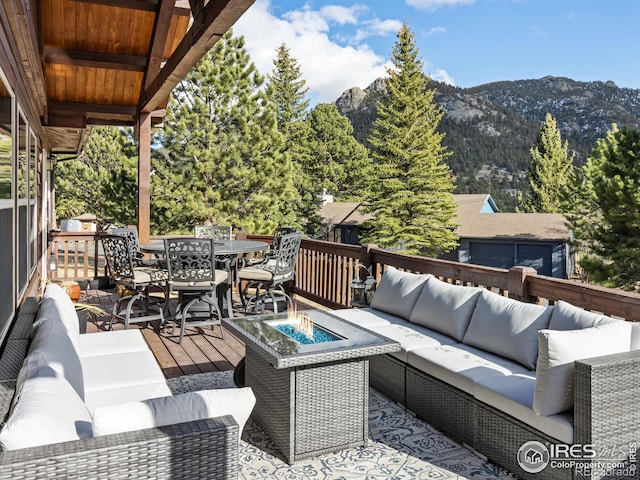 deck featuring outdoor dining area, an outdoor living space with a fire pit, and a mountain view