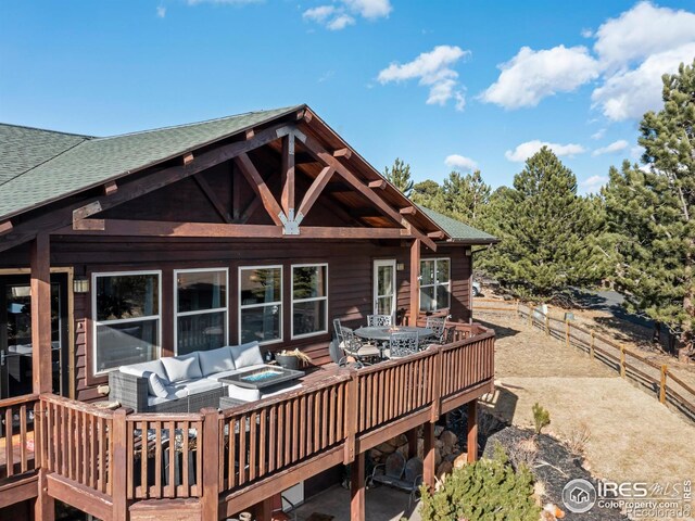 rear view of house featuring roof with shingles, fence, a deck, and an outdoor living space with a fire pit