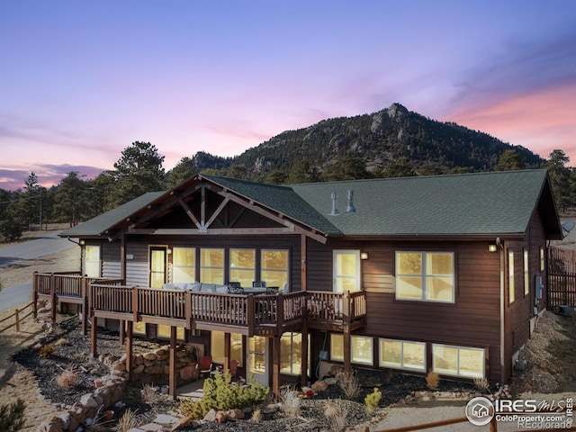 view of front of home with a shingled roof and a deck with mountain view