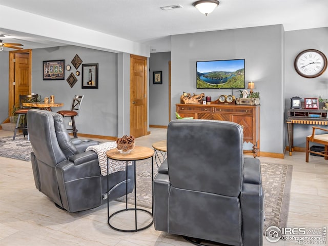 living room featuring light wood-type flooring, ceiling fan, visible vents, and baseboards