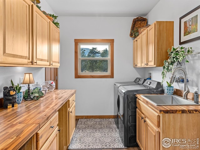 laundry room featuring baseboards, cabinet space, independent washer and dryer, and a sink