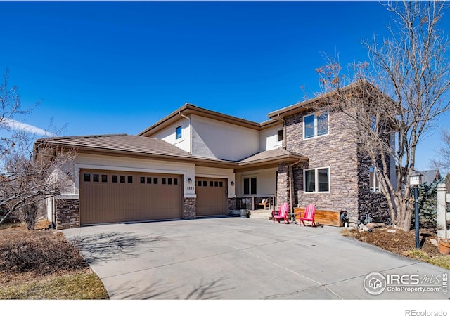 view of front of house featuring concrete driveway, stone siding, an attached garage, and stucco siding