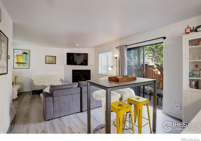 living room with light wood-style floors, a fireplace, and baseboards