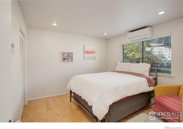 bedroom featuring a wall unit AC, light wood-style flooring, and recessed lighting