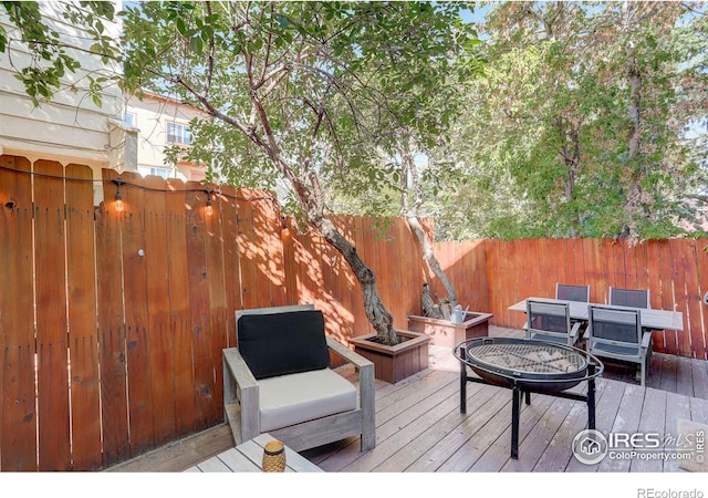 wooden terrace featuring a fenced backyard and a fire pit