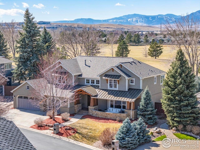 view of front facade with concrete driveway, a standing seam roof, metal roof, a mountain view, and a garage