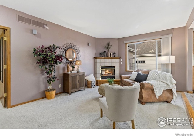 living area with carpet flooring, a tile fireplace, visible vents, and baseboards