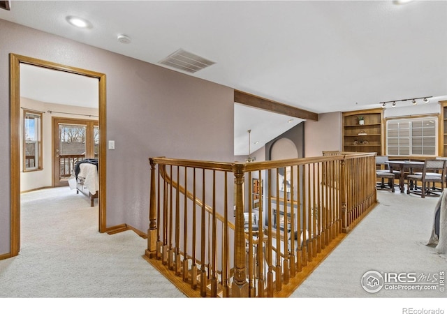 corridor with vaulted ceiling with beams, carpet flooring, an upstairs landing, visible vents, and baseboards