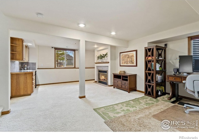 office space with baseboards, light colored carpet, a fireplace with flush hearth, a sink, and recessed lighting