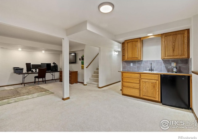 kitchen featuring tasteful backsplash, light colored carpet, brown cabinets, refrigerator, and a sink