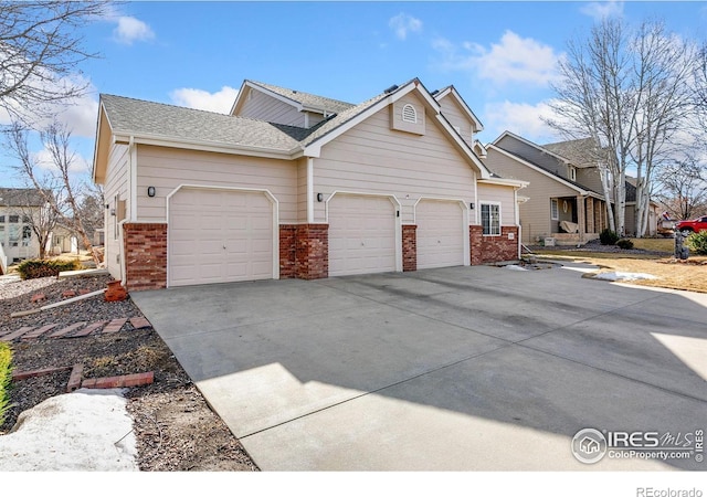 view of front of property featuring driveway, brick siding, and an attached garage