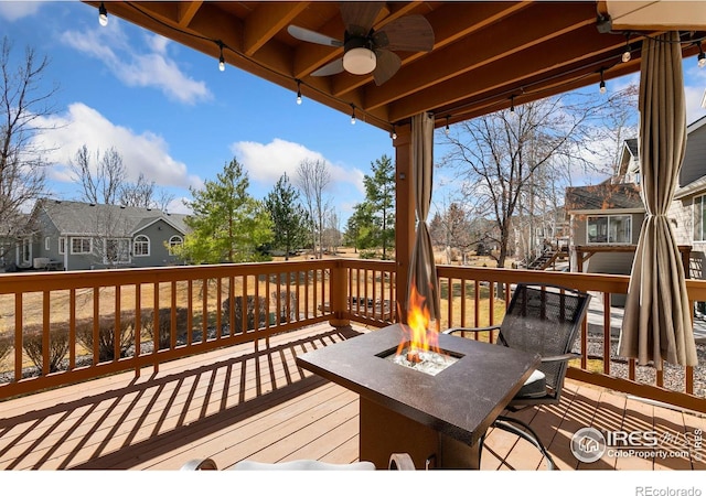 deck with a fire pit, a residential view, and a ceiling fan