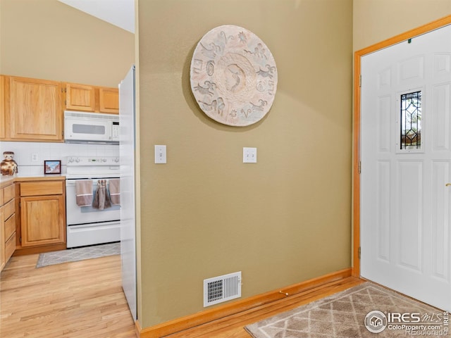 foyer entrance with light wood-type flooring, visible vents, and baseboards