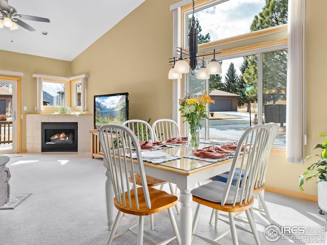 dining space with high vaulted ceiling, a wealth of natural light, a tiled fireplace, and carpet