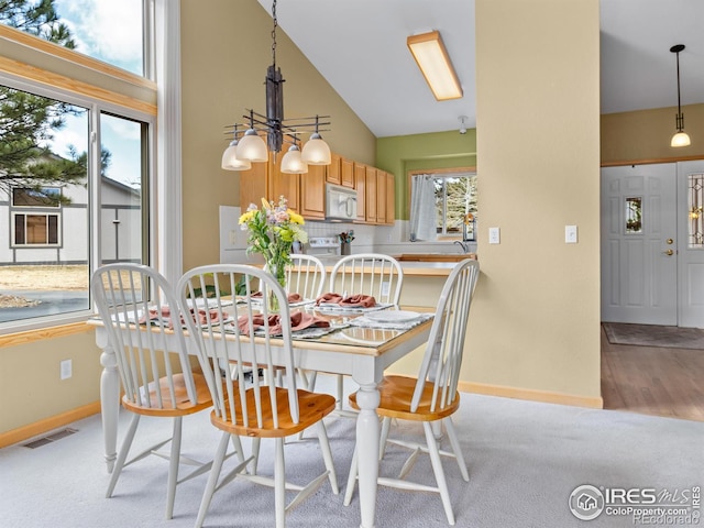 dining area with high vaulted ceiling, light carpet, visible vents, baseboards, and an inviting chandelier