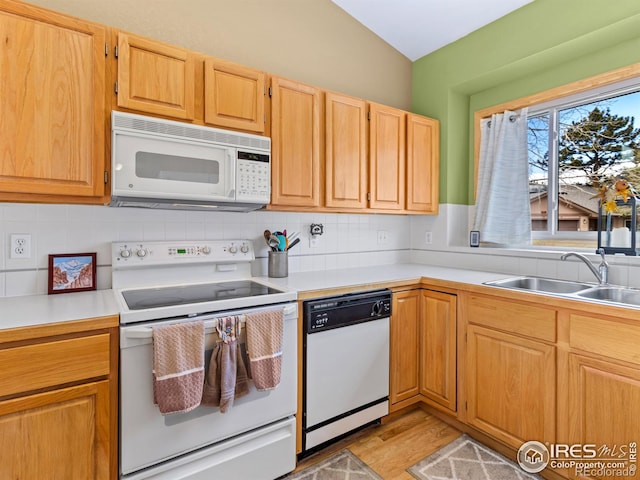 kitchen with white appliances, decorative backsplash, light countertops, light wood-style floors, and a sink