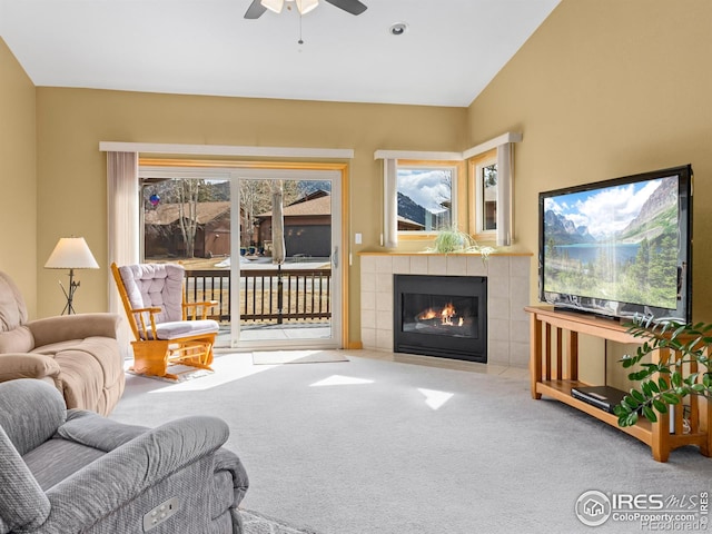 carpeted living room featuring a fireplace, vaulted ceiling, and a ceiling fan