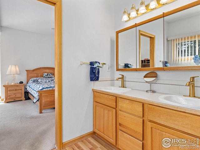 bathroom featuring baseboards, a sink, ensuite bath, and double vanity