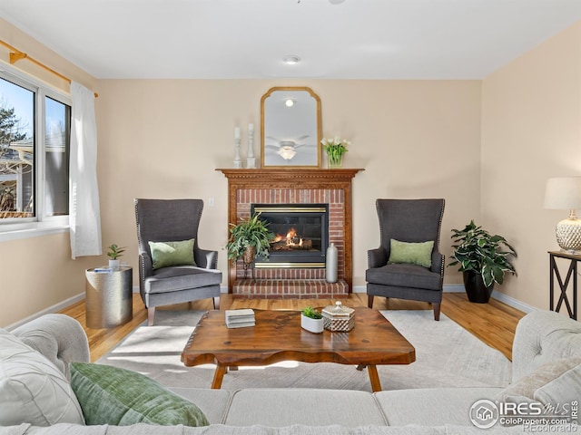 sitting room featuring a brick fireplace, wood finished floors, and baseboards