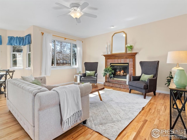 living room featuring ceiling fan, a fireplace, wood finished floors, and baseboards